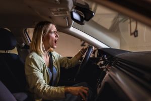 Young blonde woman driving in garage angry and stressed.