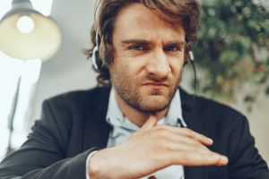 Close up portrait of an angry businessman with headset having stressful online conversation